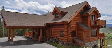 Northern view of log house and covered drive.