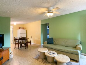 Living room has cable TV, sofa, 2 chairs, 3 tables, 2 stools & a cupboard