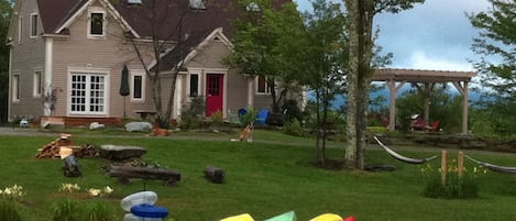 Summer view of the main house from the pond-- pergola, firepit, kayaks & hammock