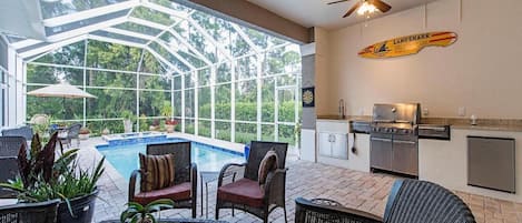 Half covered lanai with pool, hot tub, grill and dining area