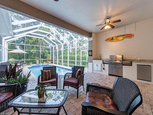 Half covered lanai with pool, hot tub, grill and dining area