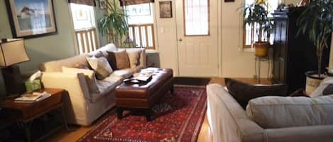 Living room w/ comfy couch, oversized chair, flat screen TV, cable, DVD, stereo.