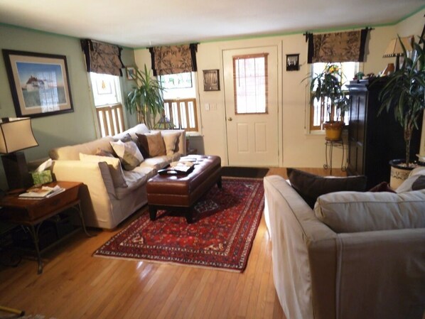 Living room w/ comfy couch, oversized chair, flat screen TV, cable, DVD, stereo.