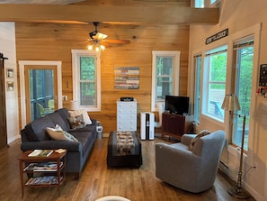 Living room side of great room, with high vaulted ceiling and natural oak wall.