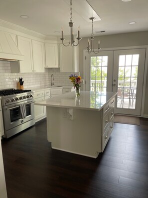 Kitchen features stainless steel appliances, quartz countertops, breakast bar.