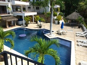 Large salt water pool with heated whirlpool, fountain, palapas, and outdoor bar