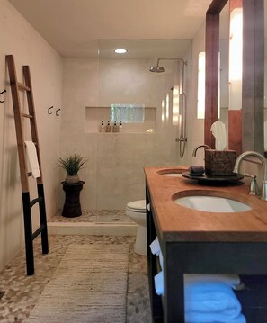Microcrete master bathroom with pebbled floor, jet tub and teak double vanities