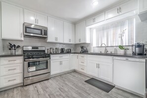 Renovated kitchen with pots, pans, cooking utensils, knifes, plates and cutlery
