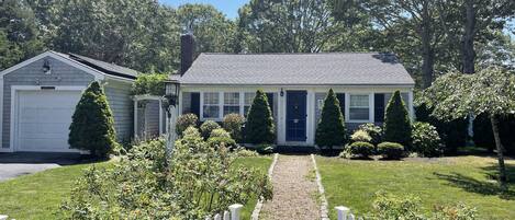 A cobblestone lined walk, white picket fence, and well maintained landscaping.