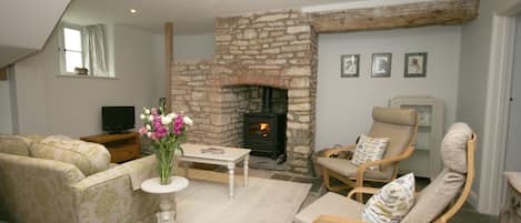 Sitting room with wood-burner and circular stone staircase hidden in the corner.