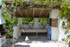 Greek-style white-washed BBQ under merlot vine.