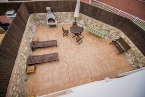 View down (from roof top solarium) to large rear terrace with BBQ and sunbeds