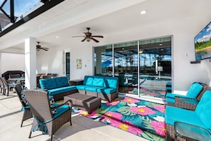 Covered lanai with dining and sofa area, with BBQ and outdoor TV