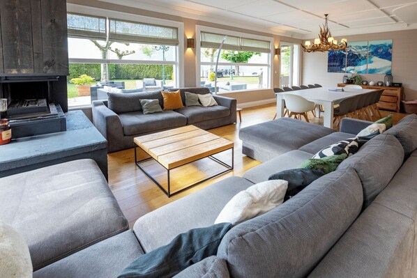 Large living / dining space with comfy couches by the fireplace and lake views