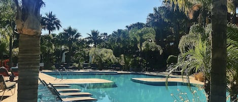 Pool view with loungers that sit in the pool with views of lush,tropical gardens