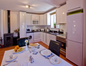 Apartment 3 another shot of the kitchen and dining area with log burner.