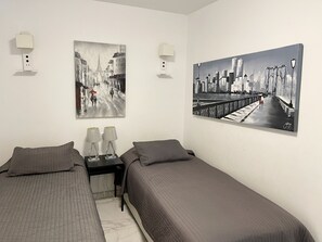 Twin bedroom with two 90 cm beds, , AC, TV on the wall in front of the beds.