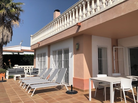 Vue de la terrasse avec les transats, le salon de jardin et la table