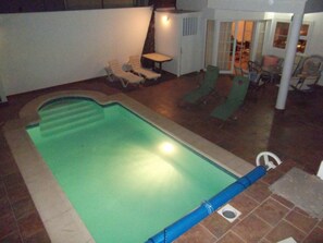 Night time view of rear patio with heated swiming pool area.