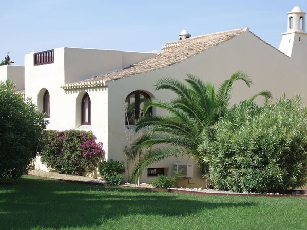 Side & back of villa amongst gardens, top sun terrace seen on the left.