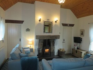 Living room with vaulted ceiling and wood burner in stone fireplace