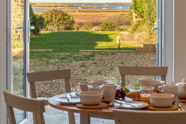 Pebble Cottage, Brancaster Staithe: Dining area with a view to the marshes and sea beyond