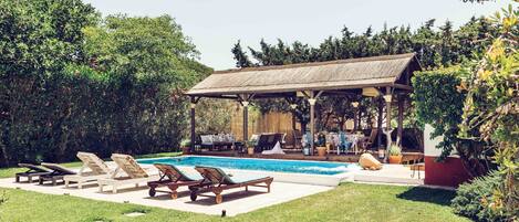 Piscina, pérgola y zona hamacas.