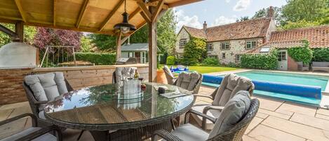 Swan Cottage, South Creake: Outdoor seating area underneath a pergola, overlooking the pool .