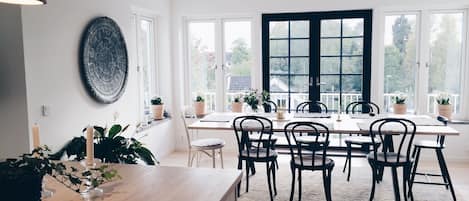 View from kitchen over dining table, step out from the black doors to the deck