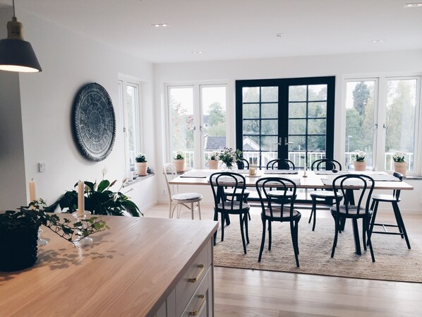 View from kitchen over dining table, step out from the black doors to the deck
