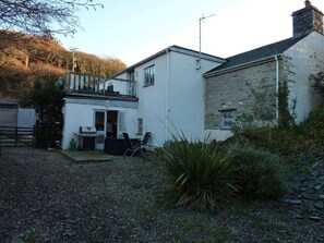 Rear patio and garden, looking towards the kitchen. Woodland at the rear.