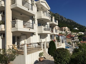 View of the terrace from gardens showing steps down to shared pool.