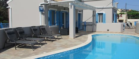 Pool with sun loungers and shaded seating area