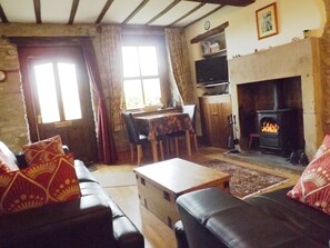 Original gritstone fireplace with wood burning stove and exposed stone wall