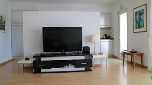 View from seating to TV with kitchen beyond