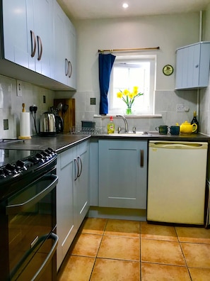 Hob, oven, microwave, fridge in well equipped kitchen.
