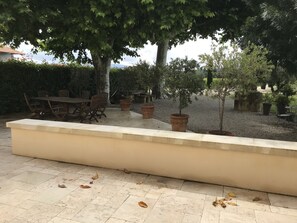 Vue de la terrasse, salon de jardin à l'ombre des platanes