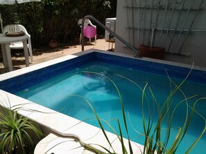 Plunge pool in private garden. Two sunloungers and seating around square table.