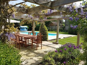 Wisteria, alliums and lavender all in bloom around pergola/outdoor dining area 