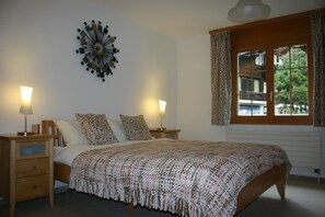 Master bedroom with king size bed, wardrobe, chest of drawers and leather chair,