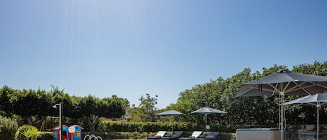 There are 8 beach chairs, umbrellas and tables around the swimming pool