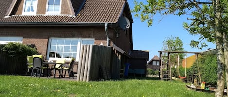 Blick auf Haus, Terrasse und Garten mit Spielgeräten