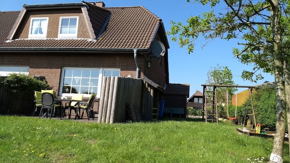 Blick auf Haus, Terrasse und Garten mit Spielgeräten