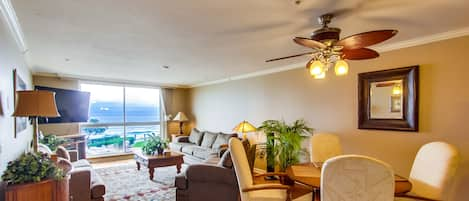 Living room with ocean view, dining seating for 4, ceiling fan, TV, overhead lighting and lamps