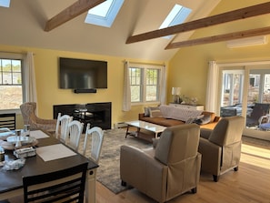 Living/dining/family room with 65" TV, soundbar, gas fireplace and skylights.