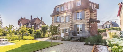 Vue sur le jardin paysager en plein soleil, la villa et la fontaine