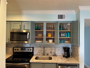 Kitchen stocked with silverware, pots, pans, cooking utensils and an ice maker.