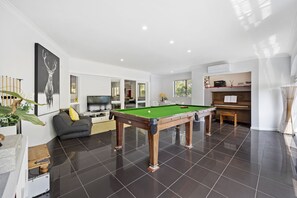 Full size pool table in games room, with piano, games tables and children's TV