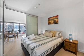 Bedroom with sliding doors opening to open-spaced lounge.
