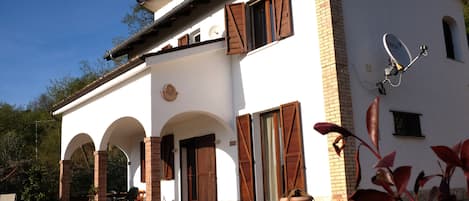 Front of house with portico and terrace above.